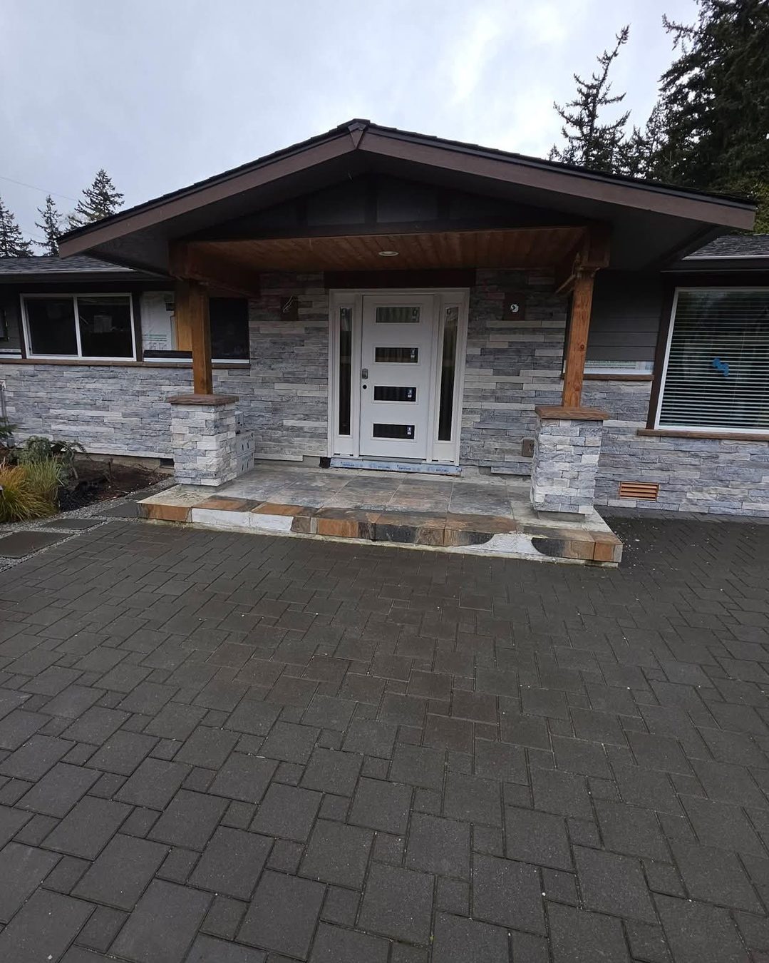 Front entry rebuilt by North End Construction — stacked-stone facade, cedar posts, tile landing and paver courtyard