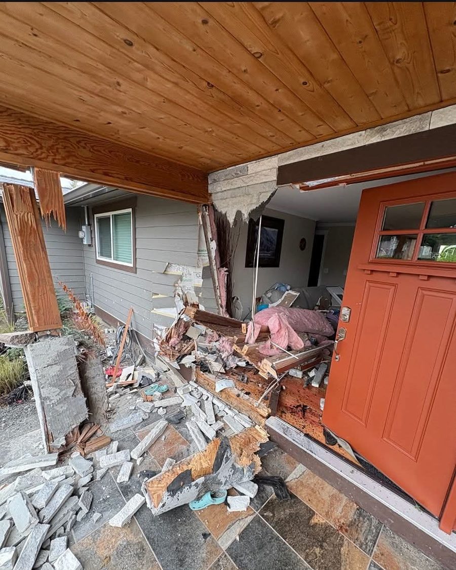 Front entry with structural damage — porch post snapped, stone wall opened to the framing
