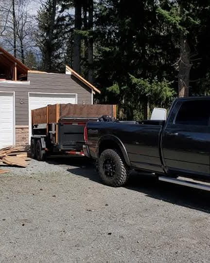 Garage mid-build with siding started, dump trailer and North End crew truck on site